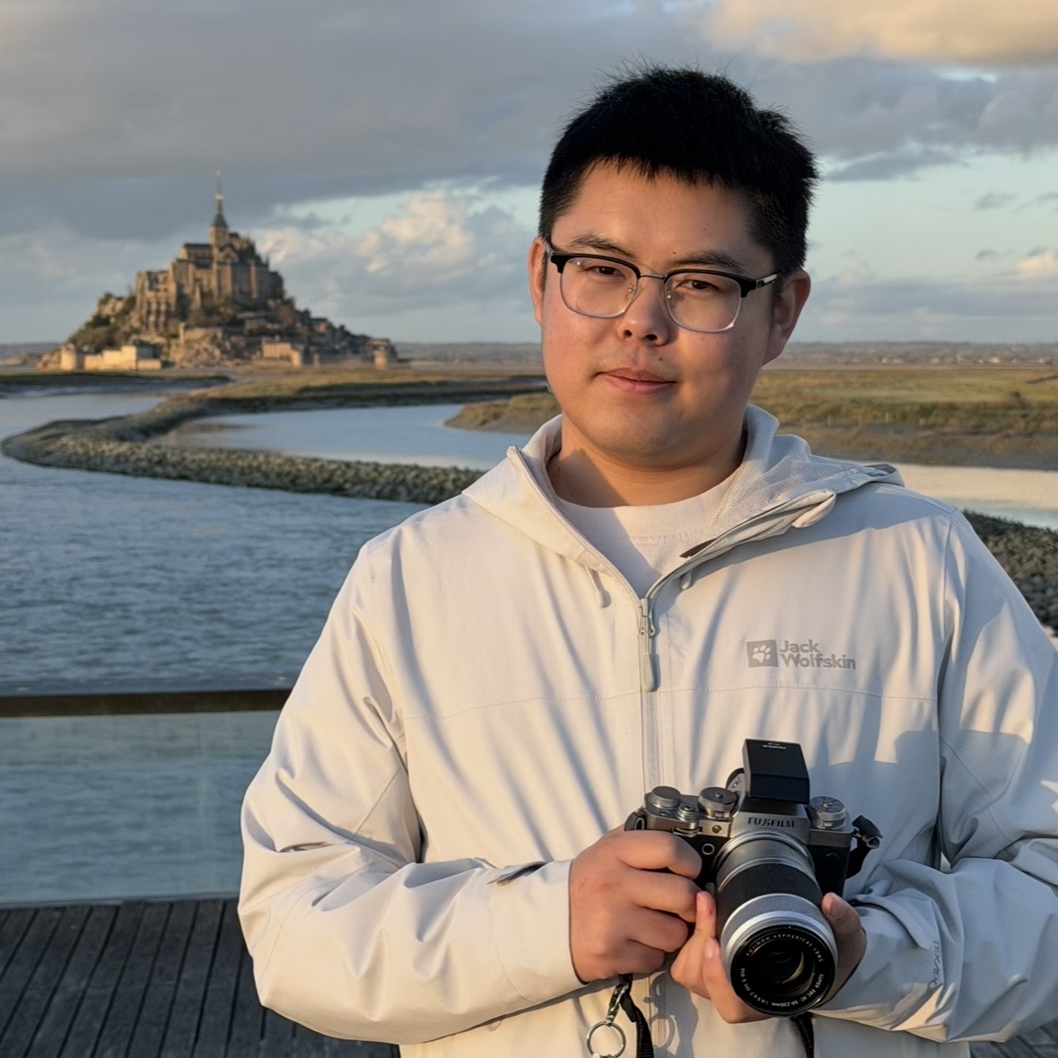 Xihao Zhang holding a camera near Mont Saint-Michel